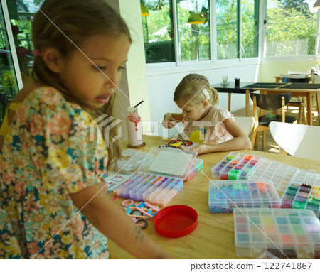 Teacher in workshop teched two girls how to assemble a thermo mosaic  122741867