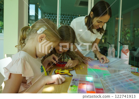 Teacher in workshop teched two girls how to assemble a thermo mosaic  122741913