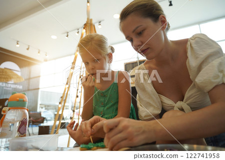 Mother and her daughter paint Halloween cookies  122741958