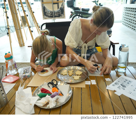 Mother and her daughter paint Halloween cookies  Mother and her daughter paint Halloween cookies  122741995