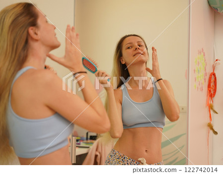 Young woman in a modern bathroom washing her face and brushing her teeth Young woman in a modern bathroom washing her face and brushing her teeth 122742014