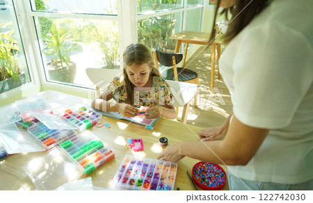 Teacher in workshop teched two girls how to assemble a thermo mosaic  122742030