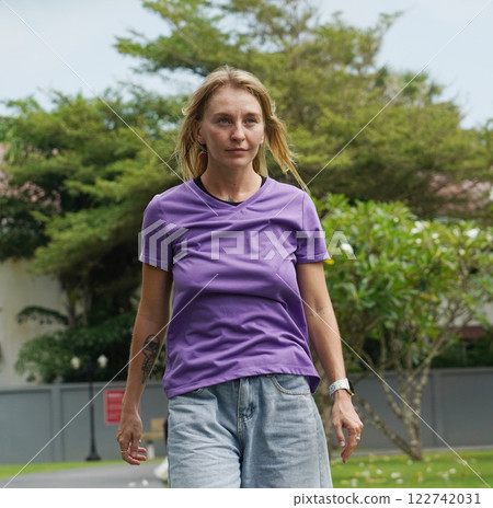 A woman is rollerblading gracefully on a road located in a park A woman is rollerblading gracefully on a road located in a park 122742031