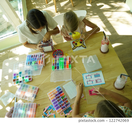 Teacher in workshop teched two girls how to assemble a thermo mosaic  122742069