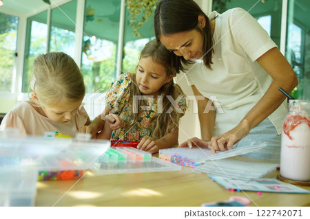 Teacher in workshop teched two girls how to assemble a thermo mosaic Teacher in workshop teched two girls how to assemble a thermo mosaic 122742071