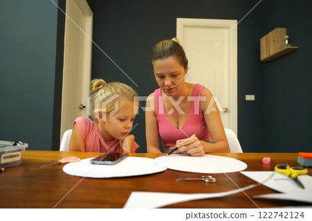 A mother and her young daughter engage in a colorful painting activity  122742124