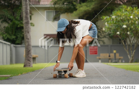 A young woman is skillfully riding a skateboard down a scenic park 122742182