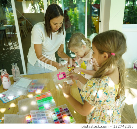 Teacher in workshop teched two girls how to assemble a thermo mosaic Teacher in workshop teched two girls how to assemble a thermo mosaic 122742193