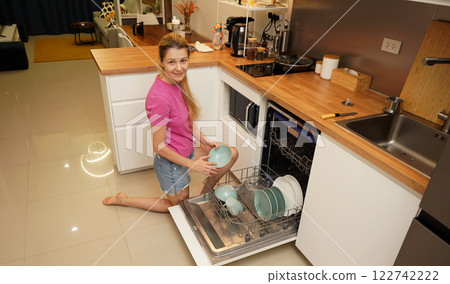 Young woman takes dishes out of the dishwasher machine 122742222