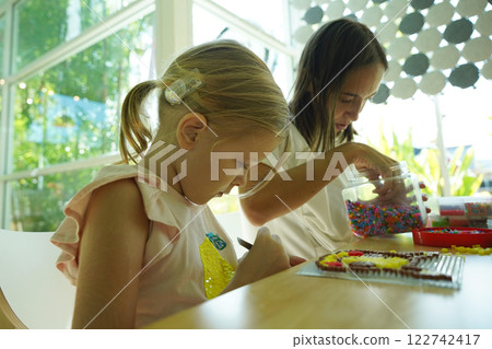 Teacher in workshop teched two girls how to assemble a thermo mosaic Teacher in workshop teched two girls how to assemble a thermo mosaic 122742417