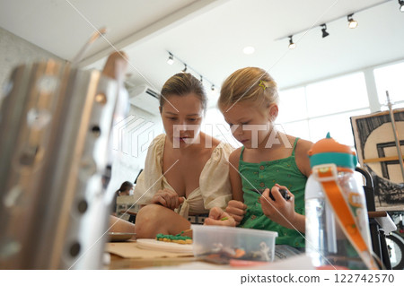 Mother and her daughter paint Halloween cookies  122742570