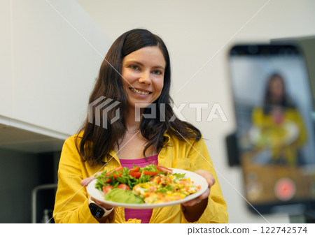Young woman is broadcasting live from workshop how to prepare a vegetarian food Young woman is broadcasting live from workshop how to prepare a vegetarian food 122742574