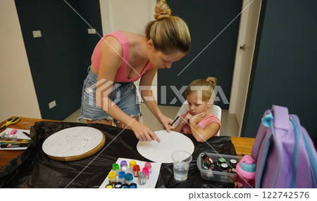 A mother and her young daughter engage in a colorful painting activity A mother and her young daughter engage in a colorful painting activity 122742576