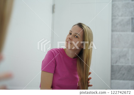 A woman is expertly styling her hair using a blow dryer and brush while in the bathroom 122742672