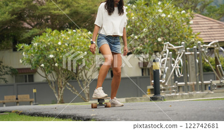A young woman is skillfully riding a skateboard down a scenic park 122742681