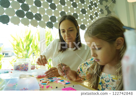 Teacher in workshop teched two girls how to assemble a thermo mosaic  122742848