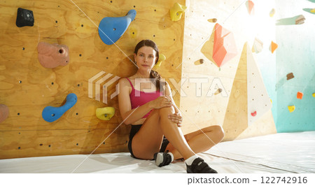 A strong female climber climbs an artificial wall with colorful grips A strong female climber climbs an artificial wall with colorful grips 122742916