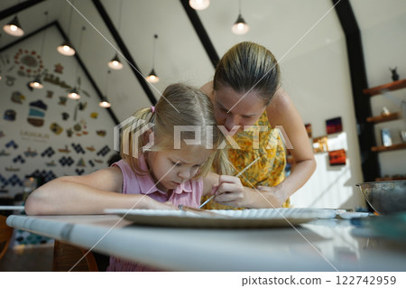A young mother and her daughter enjoy a creative art session at home  122742959