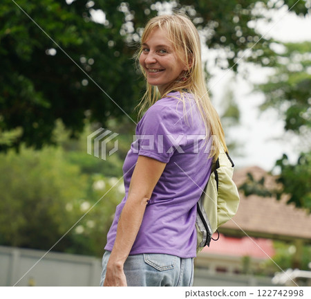 A woman is rollerblading gracefully on a road located in a park 122742998