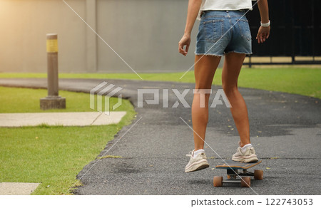 A young woman is skillfully riding a skateboard down a scenic park 122743053