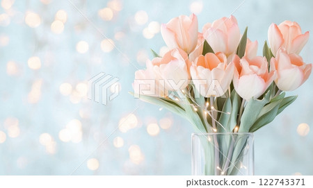 Bouquet of soft pink tulips in vase against sparkling light blue background 122743371
