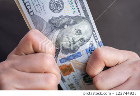Cropped shot view of someone holding one hundred American dollar banknotes in hands. The US Dollar is the currency of United States. 122744925