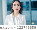 Smart working woman with a business suit is standing and posting in front of a blur office environment background created with generative AI technology 122746659