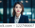 Smart working woman with a business suit is standing and posting in front of a blur office environment background created with generative AI technology 122746667