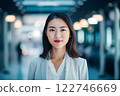Smart working woman with a business suit is standing and posting in front of a blur office environment background created with generative AI technology 122746669