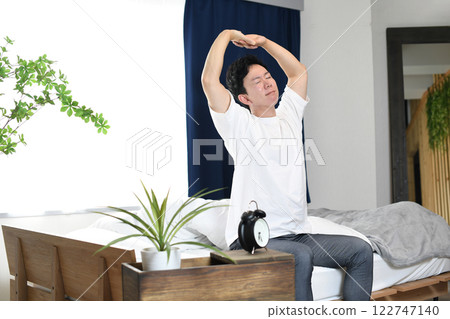 A man stretching on his bed after waking up A man stretching on his bed after waking up 122747140