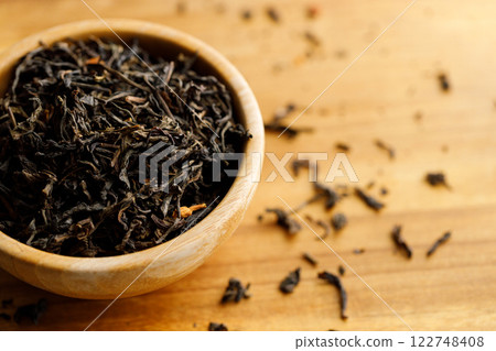 Japanese or Chinese jasmine tea leaf in wooden bowl on wooden background. Japanese or Chinese jasmine tea leaf in wooden bowl on wooden background. 122748408