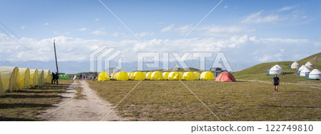 View on expedition mountaineering camp with many yellow tents and yurts, Pamir Mountains, Kyrgyzstan 122749810