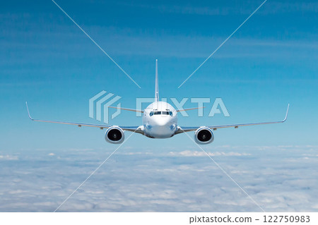 Front view of the white passenger airliner flying in the air above the clouds 122750983
