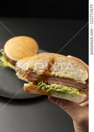 Lift up the ham cutlet burger with your hands Lift up the ham cutlet burger with your hands 122751674