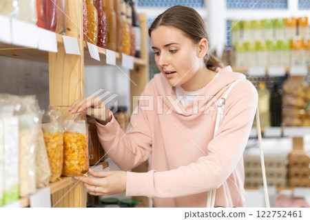Girl customer in supermarket choose and take flakes from shelve, buy food stuff in grocery store 122752461