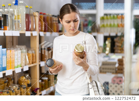 Woman carefully chooses canned beans and lentils Woman carefully chooses canned beans and lentils 122752472