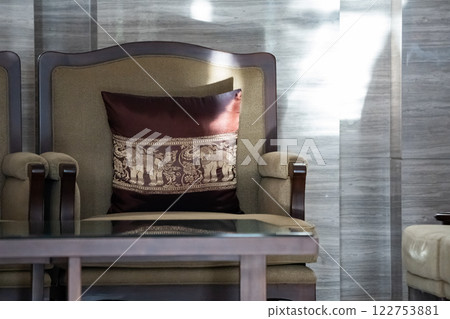 Sunlight shines on the elegant wooden sofa upholstered with ivory velvet fabric and a round coffee table set in a living room. 122753881