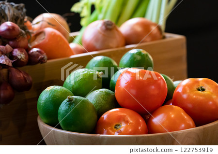 Vegetable tomato and lime in wood bowl with blur background carrot, onion, and red shallot in wood box. All are in studio light. Vegetable tomato and lime in wood bowl with blur background carrot, onion, and red shallot in wood box. All are in studio light. 122753919