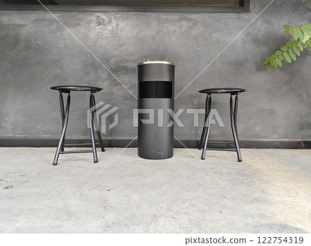 Metal bin and chairs on concrete floor. Metal bin and chairs on concrete floor. 122754319