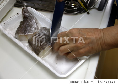 A housewife cutting up a cod fish 122755433