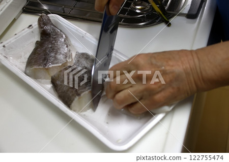 A housewife cutting up a cod fish 122755474