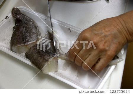 A housewife cutting up a cod fish 122755654