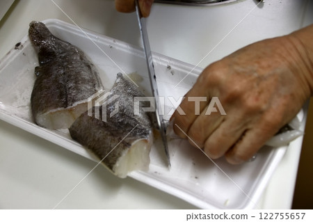 A housewife cutting up a cod fish 122755657