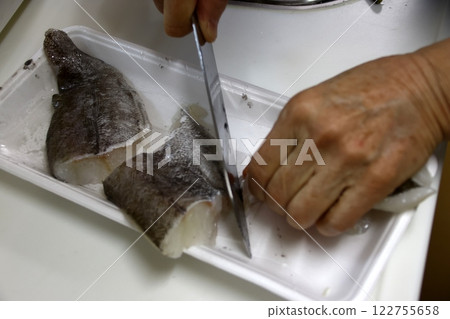 A housewife cutting up a cod fish 122755658