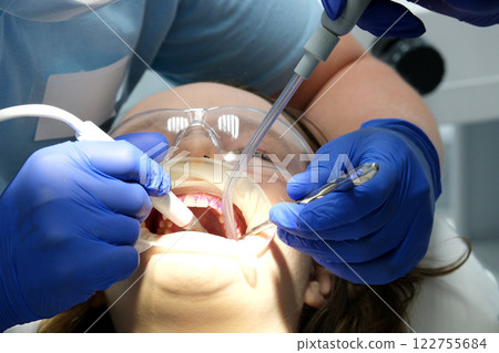 Doctor working with instruments in patient's open mouth for dental treatment 122755684