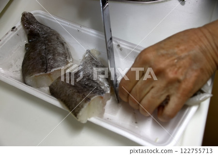 A housewife cutting up a cod fish 122755713