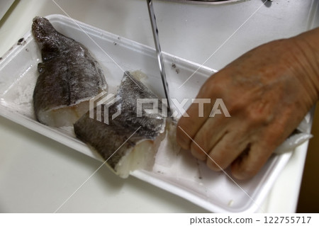 一位家庭主婦正在切鱈魚 一位家庭主婦正在切鱈魚 122755717