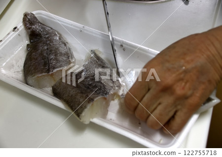 A housewife cutting up a cod fish 122755718