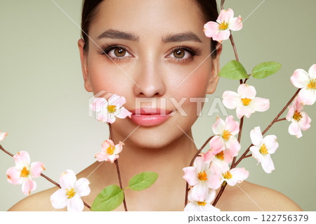 Beautiful young woman with a cherry blossom branch Beautiful young woman with a cherry blossom branch 122756379