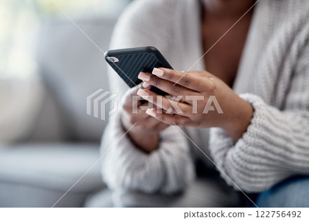 Closeup of woman hands typing on phone, sending a text message online on social media on home sofa. Female reading and replying to a work email. African American lady playing a game on mobile device. 122756492